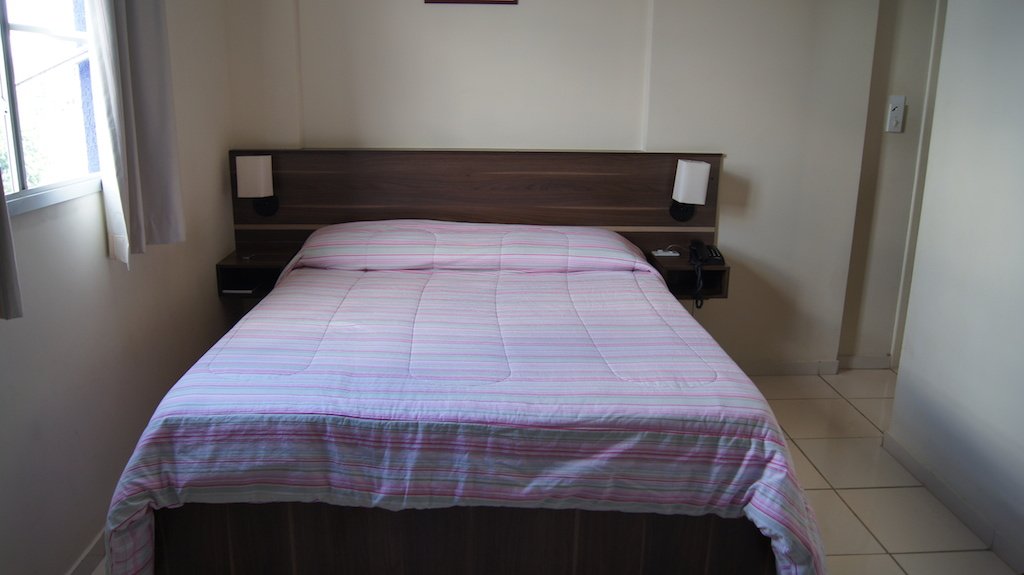 Quarto casal do Astro Hotel com a cama em destaque